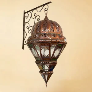 A high-quality isolated view of an ornate Moroccan lantern featuring a hand-pierced copper dome and vibrant multi-colored stained glass panels, hanging from a decorative metal wall bracket.