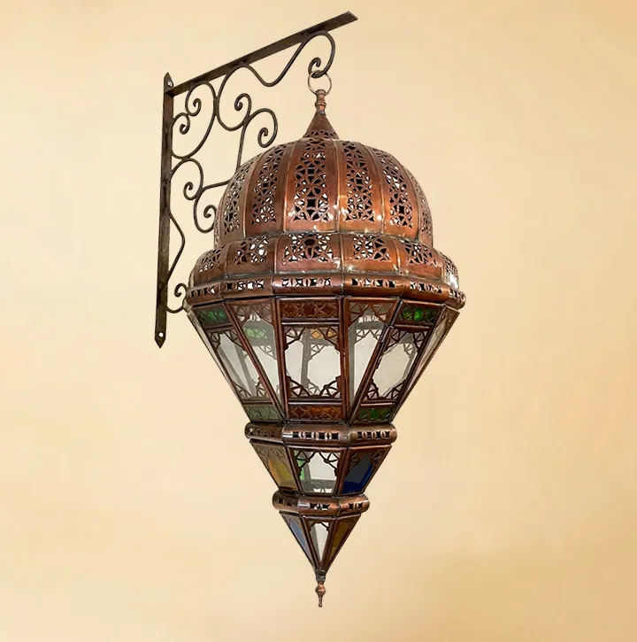A high-quality isolated view of an ornate Moroccan lantern featuring a hand-pierced copper dome and vibrant multi-colored stained glass panels, hanging from a decorative metal wall bracket.